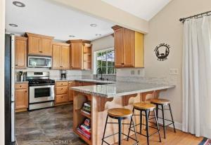 a kitchen with wooden cabinets and a island with bar stools at Charming Getaway Cabin in Lake Arrowhead