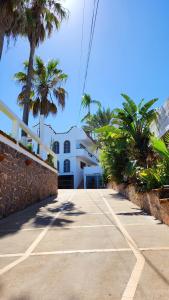 una acera frente a un edificio blanco con palmeras en Hill House Mazatlan - Bed & Breakfast en Mazatlán