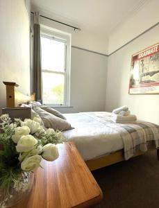 a bedroom with a bed and a table with flowers on it at Lovely Victorian Apartment in Clifton Village in Bristol