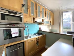 a kitchen with wooden cabinets and a stove top oven at Lovely Victorian Apartment in Clifton Village in Bristol