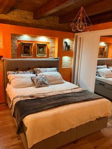 a bedroom with a large bed with orange walls at Casa Odihnei Villa & Tiny-House in Tîrnăveni