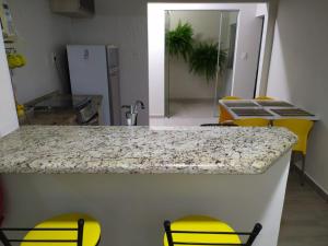 a kitchen with a counter top and yellow chairs at Casa de Maria in Aparecida