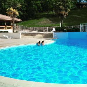 two people swimming in a large blue swimming pool at L'Occitana in Mauroux