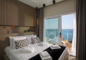 een slaapkamer met een groot bed en uitzicht op de oceaan bij Hersonissos Beach Front Suites in Chersonissos