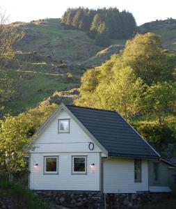 a white house with a black roof on a hill at Guesthouse in Manger, Radøy Island in Kollstad