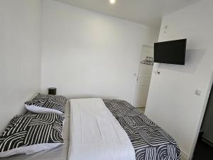 Un dormitorio con dos camas y un televisor en la pared. en Charmant studio équipé de 14m2, en Neuilly-sur-Marne