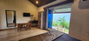 Zimmer mit einem Schlafzimmer mit einem großen Fenster und einem Schreibtisch in der Unterkunft Mysticstays Resort in Wai