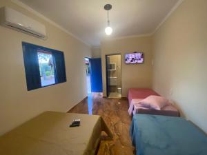 a room with two beds and a table and a window at Cantinho caipira in Aparecida