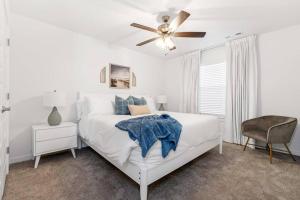 een witte slaapkamer met een bed en een plafondventilator bij Modern Elegance - Just 10 Mins to U of A in Fayetteville