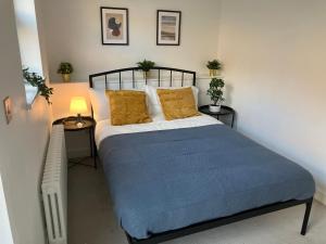 um quarto com uma cama grande com lençóis azuis e almofadas amarelas em Magnificent Refurbished 1 Bed Flat few steps to High St ! - 4 East House em Epsom