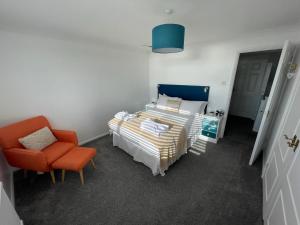 um quarto com uma cama e uma cadeira laranja em The Beach House em South Hayling