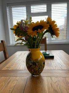 a yellow vase filled with yellow flowers on a wooden table at The Beach House in South Hayling