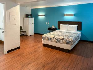 sypialnia z łóżkiem i niebieską ścianą w obiekcie Motel 6 Ontario CA Convention Center Airport w mieście Ontario