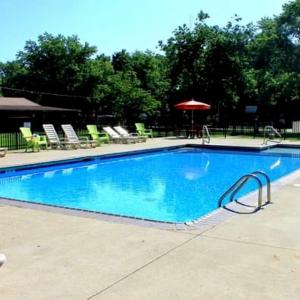 a large blue swimming pool with chairs and an umbrella at Elkhorn Creek RV Park in Frankfort