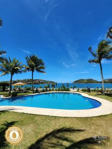 una piscina con palmeras y el océano en el fondo en Villa Raphael en Búzios