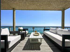 a patio with couches and a table on a balcony at Cozy House With Ocean View - PCH-R-MA in Malibu