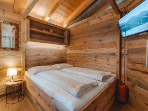 a bed in a wooden room with a tv at Chalet Hochkrimml 2 by Interhome in Krimml