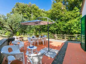 Nibbiaia的住宿－Holiday Home Podere gli Olivi by Interhome，庭院配有桌椅和遮阳伞。