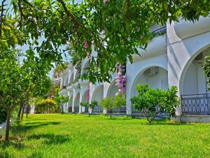 a courtyard of a building with green grass and trees at Spiros Studios in Parga