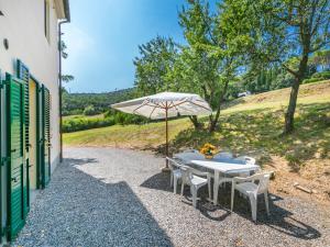 una mesa con sombrilla junto a un edificio en Apartment Podere La Madonnina-3 by Interhome, en Nibbiaia