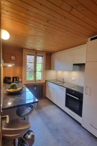ツヴァイジンメンにあるApartment Bachhüsi by Interhomeの白いキャビネットと木製の天井が備わるキッチン