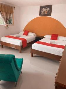 a bedroom with two beds and a chair in it at Hacienda Ixtlan Cozumel in Cozumel
