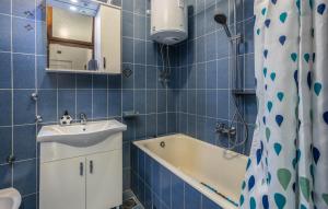 La salle de bains est pourvue de carrelage bleu, d'un lavabo et d'une baignoire. dans l'établissement Apartments Drazen, à Crikvenica