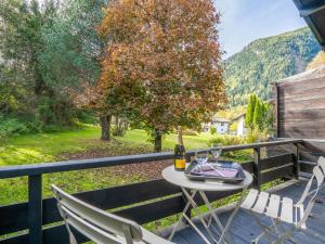 una mesa con una botella de vino y 2 sillas en el balcón en Holiday Home Les Mazots de La Renardiere by Interhome, en Chamonix-Mont-Blanc