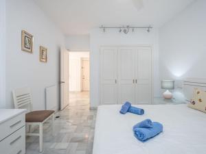 a white bedroom with two blue pillows on a bed at Apartment Jardines Del Mar by Interhome in Marbella