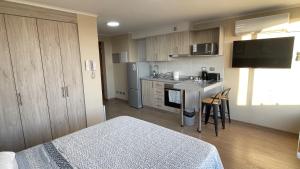 a bedroom with a bed and a kitchen with a counter at Depto central, parking, moderno in Chillán