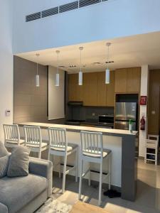 a kitchen with a bar with chairs and a couch at Sharjah Brand New Apartment in Sharjah