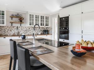 une cuisine avec des placards blancs et une table en bois dans l'établissement Holiday Home Villa Blommelund by Interhome, à Kolmården