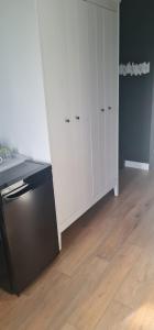 uma cozinha com um frigorífico preto e um armário branco em Rybacka em Augustów