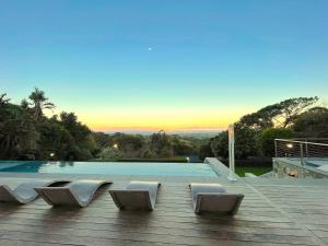 a swimming pool with chairs on a wooden deck at Camelot Villa in Cape Town