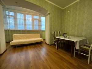 a room with a table and a couch and a table and chairs at Элитная квартира возле гипермаркета Дины in Aktobe