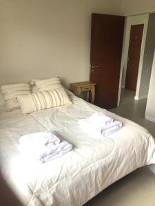 Una cama blanca con toallas encima. en Gray Fox Apartments San Martin en Ushuaia