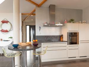 a kitchen with white cabinets and a table and chairs at Holiday Home Maison de Plain Pied - Vue Mer - TRP106 by Interhome in Kergador