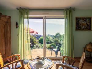 Pokój ze stołem i krzesłami oraz przesuwnymi szklanymi drzwiami w obiekcie Holiday Home Tal ar Mor - LPU100 by Interhome w mieście Le Pouldu