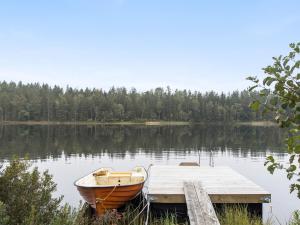 un barco sentado en un muelle en un lago en Holiday Home Angsjö Torp by Interhome, en Backaryd