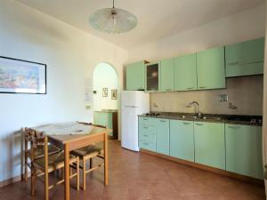 カポリーヴェリにあるApartment Oasis 3 by Interhomeのキッチン(緑のキャビネット、テーブル、冷蔵庫付)