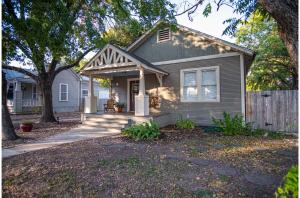 een grijs huis met een veranda en een hek bij Chic Downtown Farmhouse with Garden and BBQ Grill in San Antonio