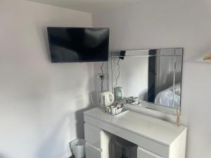 a bathroom with a sink and a tv on a wall at Coach house hotel in Royston +33 photos