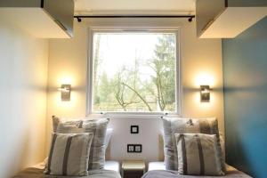 Schlafzimmer mit einem Fenster und einem Bett mit Kissen in der Unterkunft La Cabane du Pêcheur à 10min de Disneyland Paris - Cabane & Cabanon in Chalifert