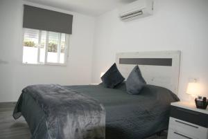 una camera da letto con un letto con cuscini blu e una finestra di Bungalow en Los Balcones planta baja manzana 5 no 18 StayOrihuelaCosta #PRP004 ad Alicante Altre 30 foto