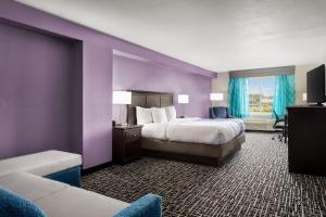 ein Hotelzimmer mit lila Wänden, einem Bett und einem Sofa in der Unterkunft La Quinta by Wyndham Cookeville in Cookeville