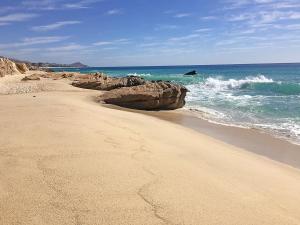 einen Sandstrand mit Felsen im Ozean in der Unterkunft Excelsior Residence in Cabo San Lucas