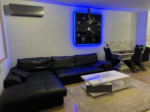 ein Wohnzimmer mit einem Sofa und einer Uhr an der Wand in der Unterkunft Apartments Las Tres Palmas in Sofia