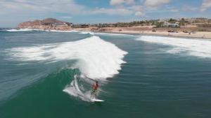 Ein Mann reitet eine Welle auf einem Surfbrett im Ozean in der Unterkunft Excelsior Residence in Cabo San Lucas