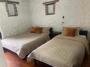 two beds sitting next to each other in a room at Hotel Colonial Centro Historico in Tunja
