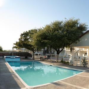 einem Pool vor einem Gebäude mit Bäumen in der Unterkunft Hotel Quinta San Carlos Inn in Manuel Valdez